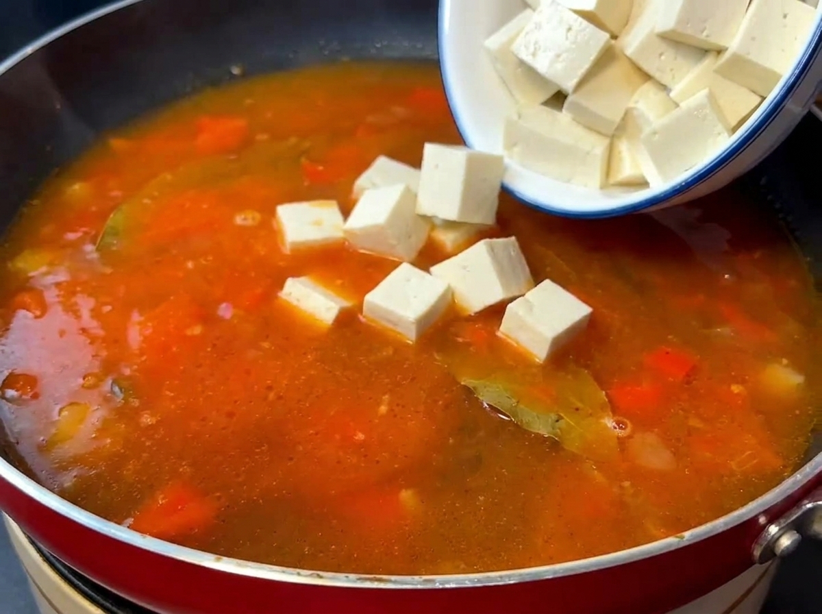 볶은 토마토 베이스에 연두부와 볶은 소고기를 넣는 모습.