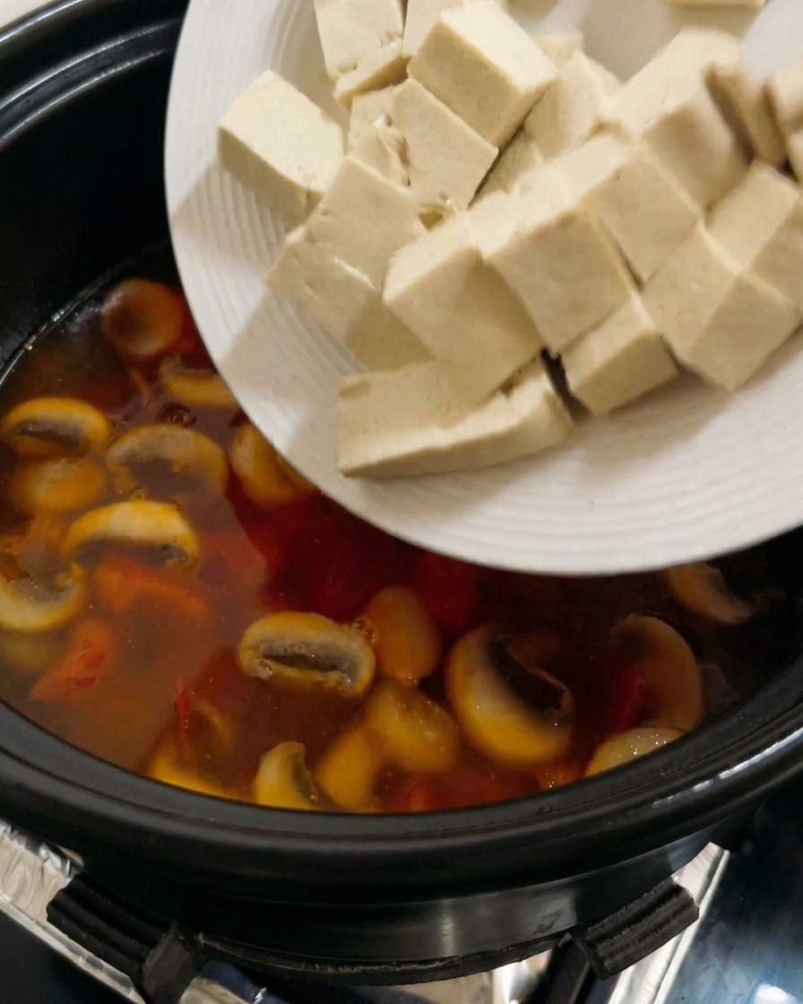끓고 있는 토마토 국물에 깍둑썰기한 두부를 넣는 모습
