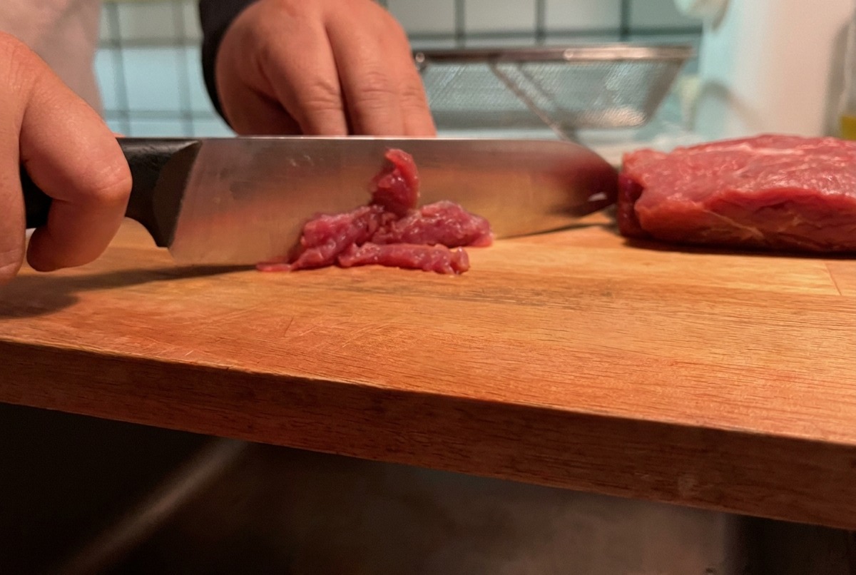 도마 위에서 돼지 살코기를 얇게 채 써는 모습.