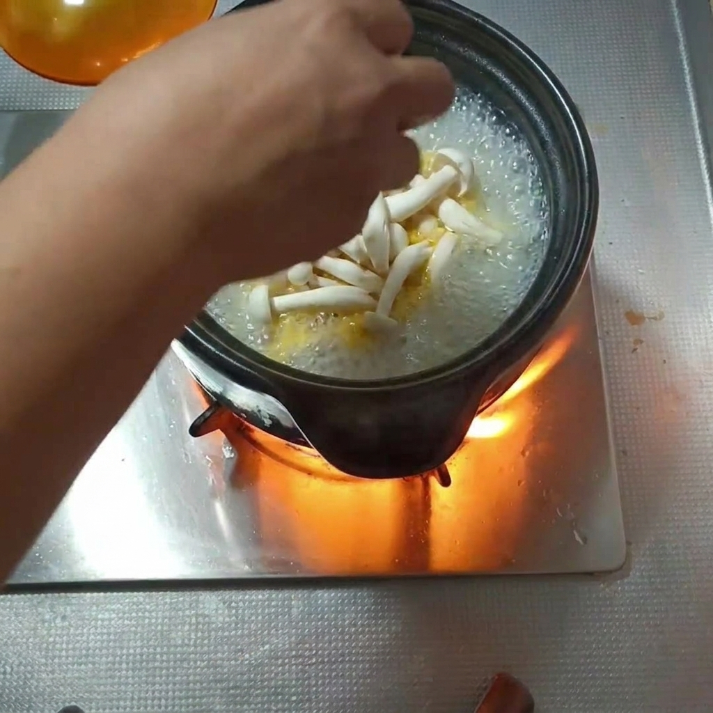 팔팔 끓는 뚝배기에 손질한 버섯을 넣는 모습.
