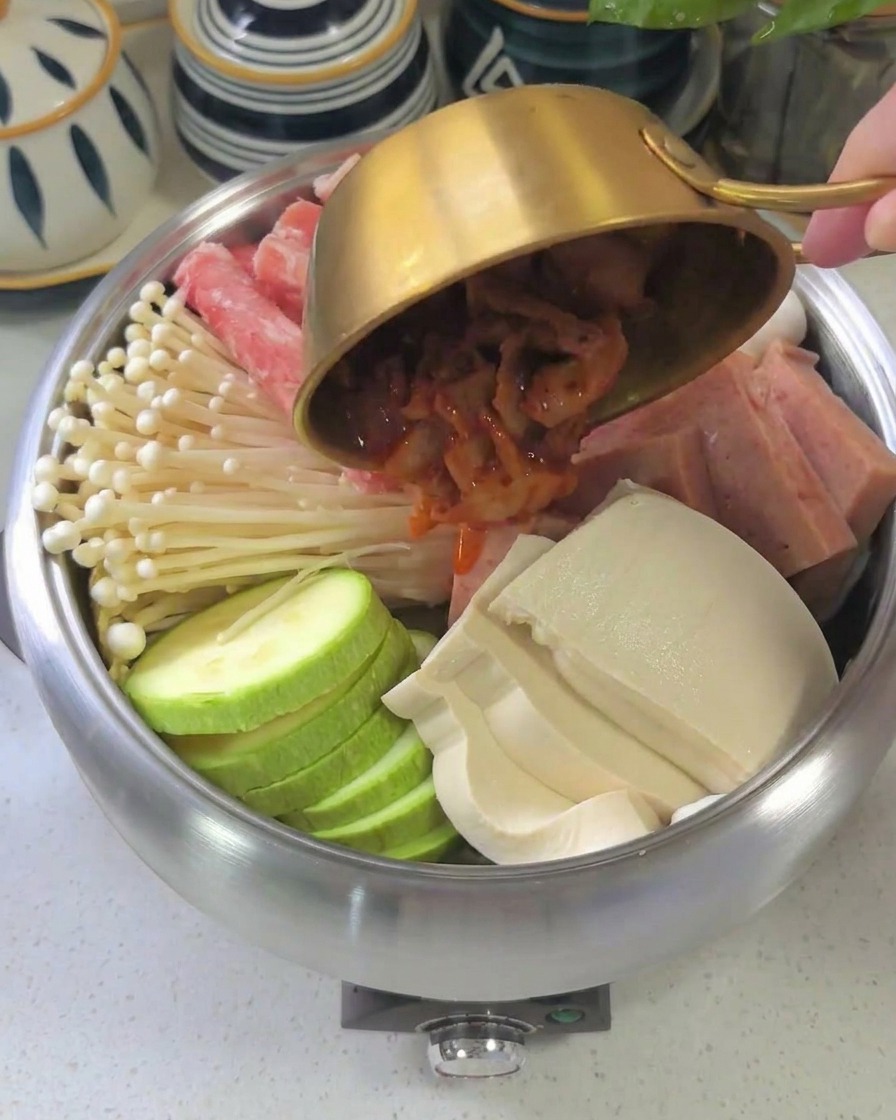 담아놓은 재료 위로 붉은 양념장을 골고루 펴 바르는 모습
