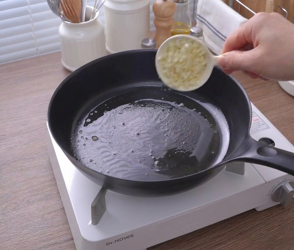 녹은 버터가 담긴 팬에 다진 마늘을 넣는 모습.