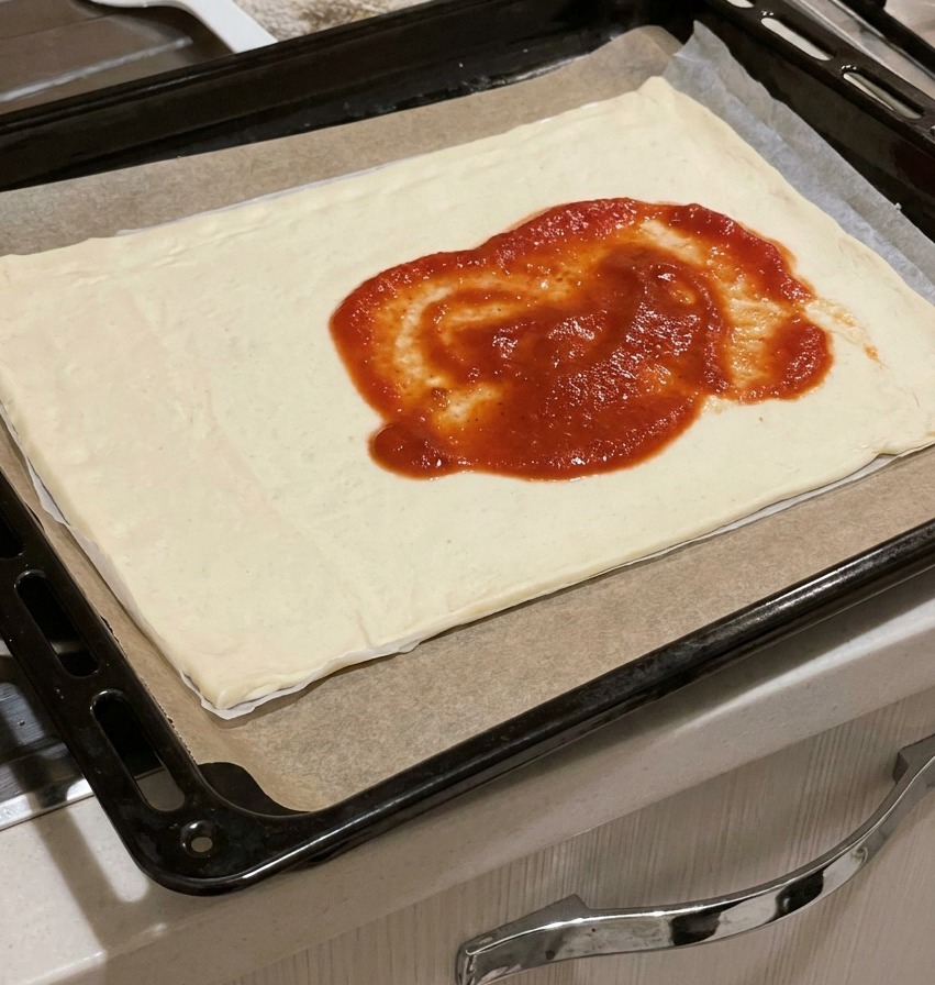 생 도우 중앙에 진한 빨간색 토마토 소스를 듬뿍 얹은 모습