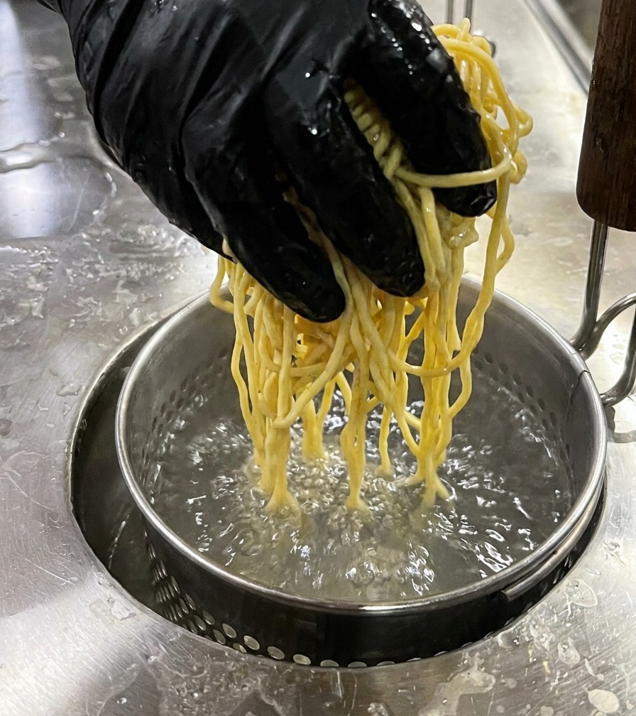 면 건지기에 담긴 생면을 끓는 물에 넣는 모습.