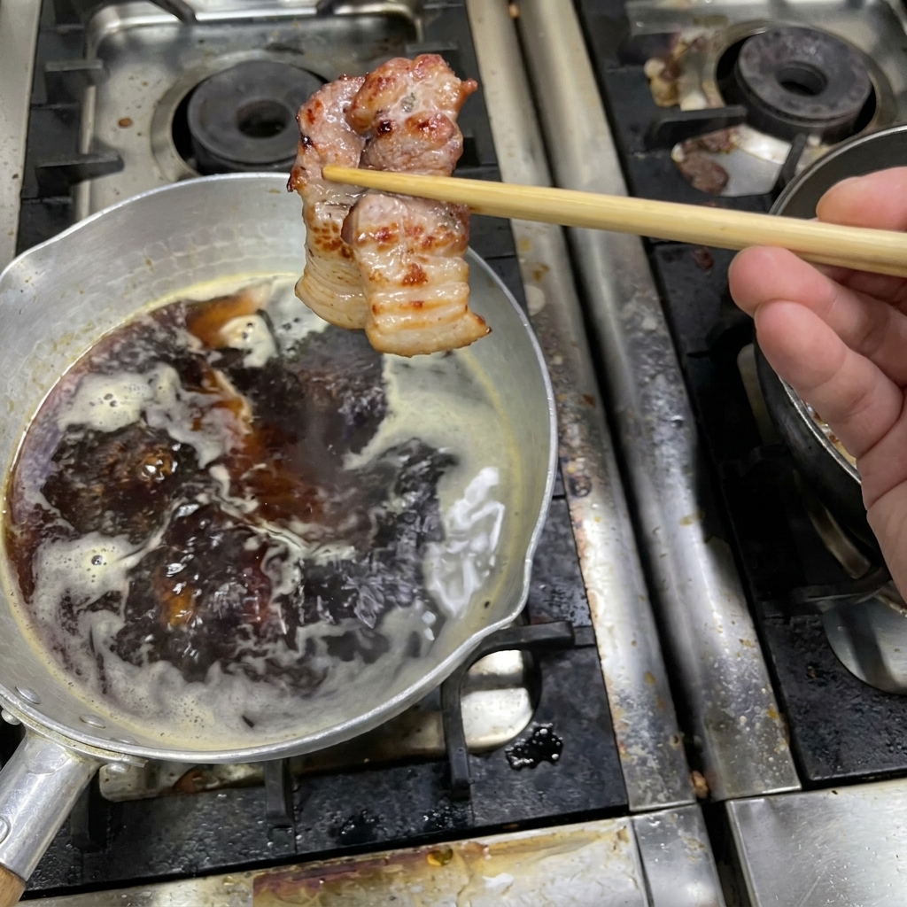 잘 구워진 삼겹살을 끓고 있는 소스 냄비에 옮겨 담는 모습