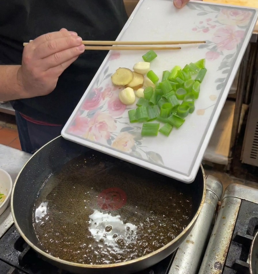 뜨거운 기름이 담긴 팬에 썰어둔 쪽파, 생강, 마늘을 넣는 모습