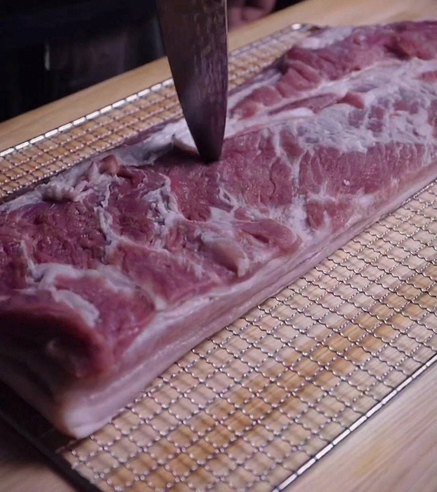 칼끝으로 삼겹살 표면에 작은 구멍을 내고 있는 클로즈업 사진.