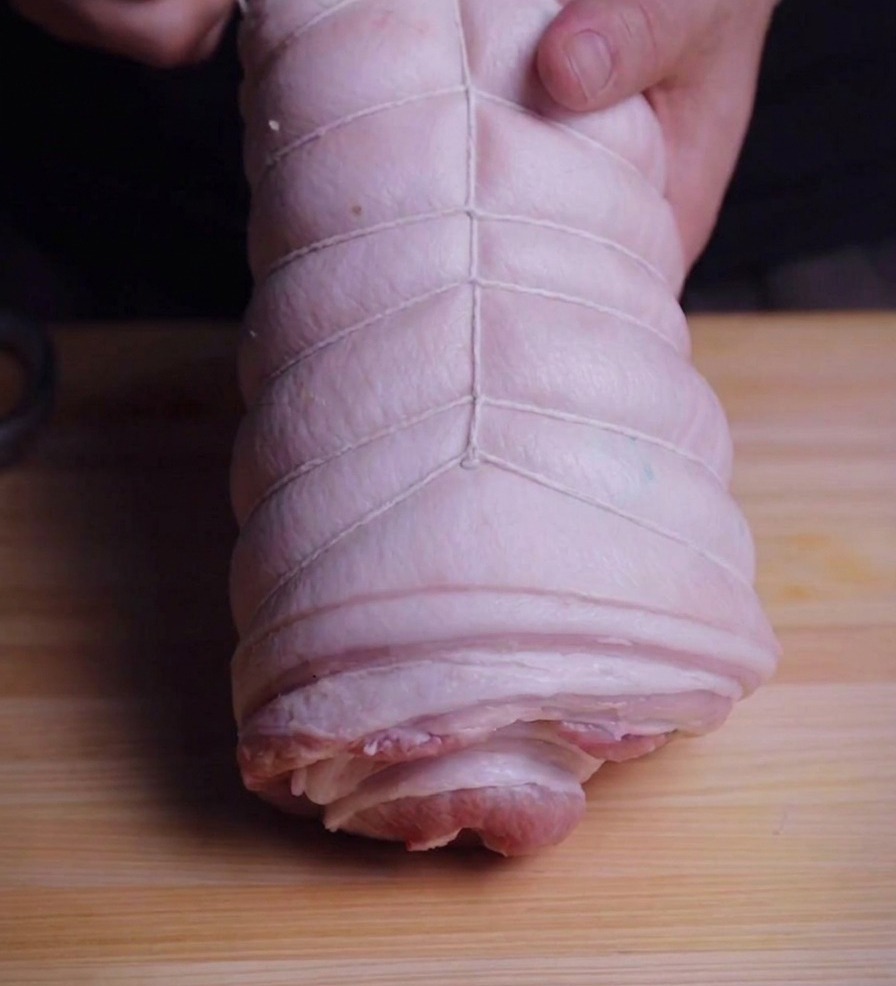 원통으로 만 삼겹살을 요리용 명주실로 촘촘하게 묶는 모습.