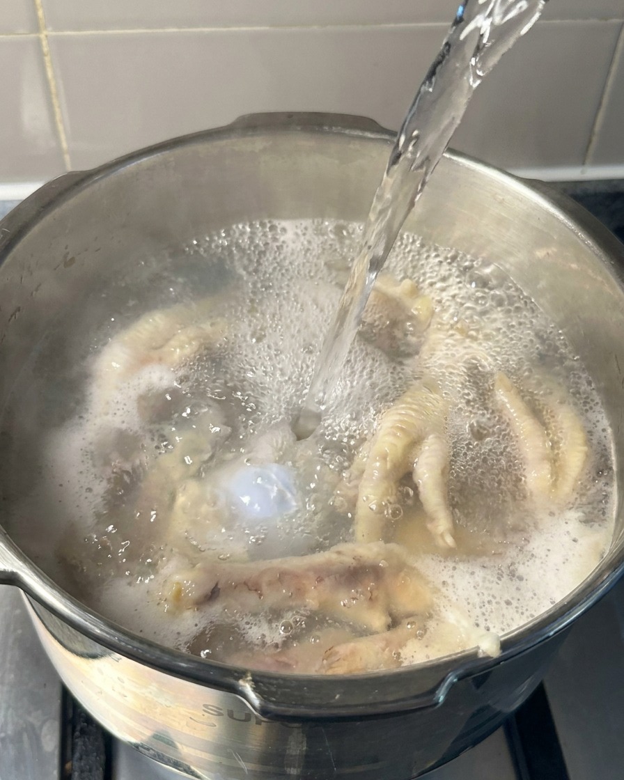 닭발과 뼈가 담긴 냄비에 끓는 물을 추가로 붓는 장면.