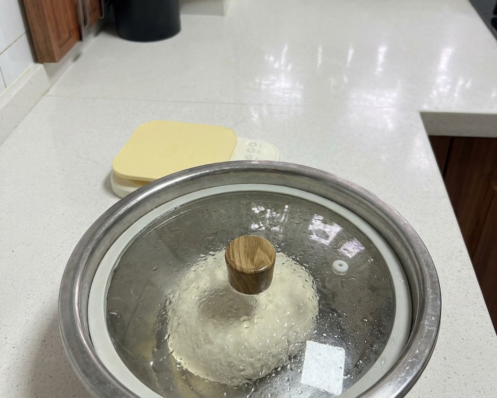 뚜껑을 덮은 스테인리스 볼 안에서 휴지 중인 반죽과 내부에 맺힌 수증기.
