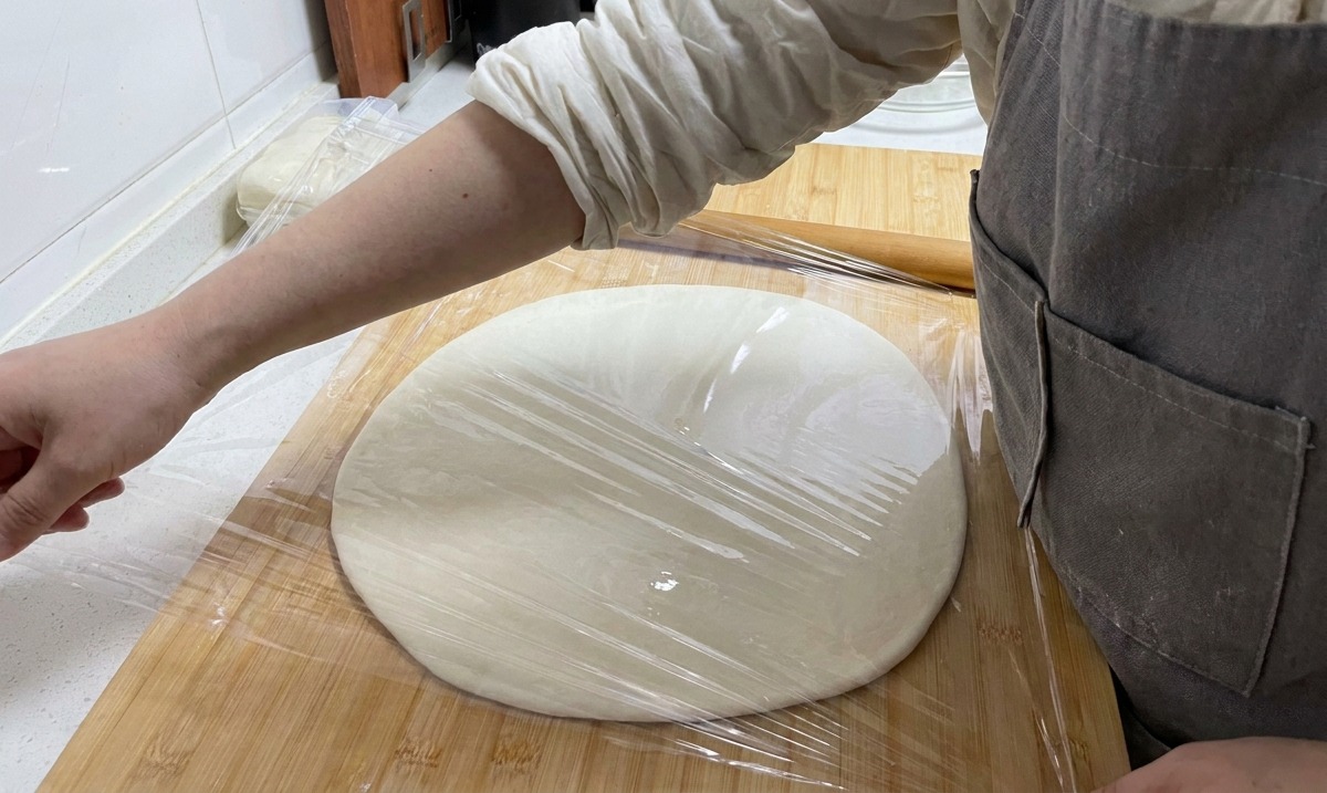 도마 위의 넓게 편 반죽 위로 투명한 랩을 꼼꼼하게 씌우는 손.