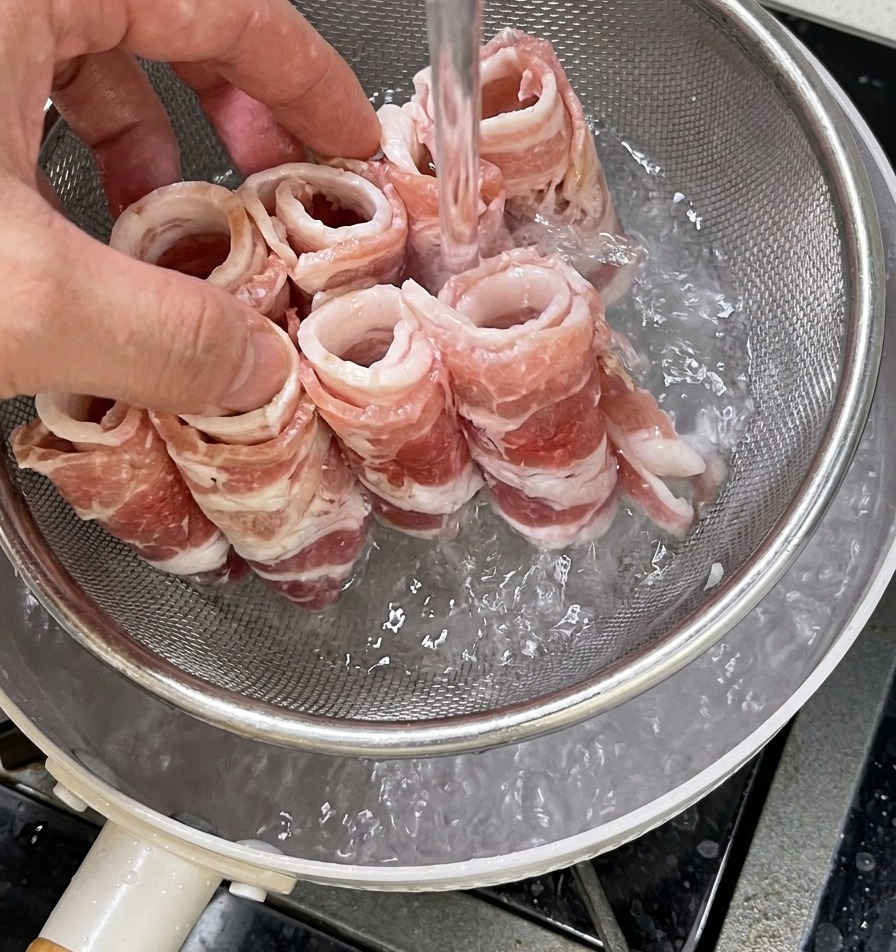 금속 채반에 담긴 생소고기를 불순물 제거를 위해 끓는 물에 넣고 데치는 모습.
