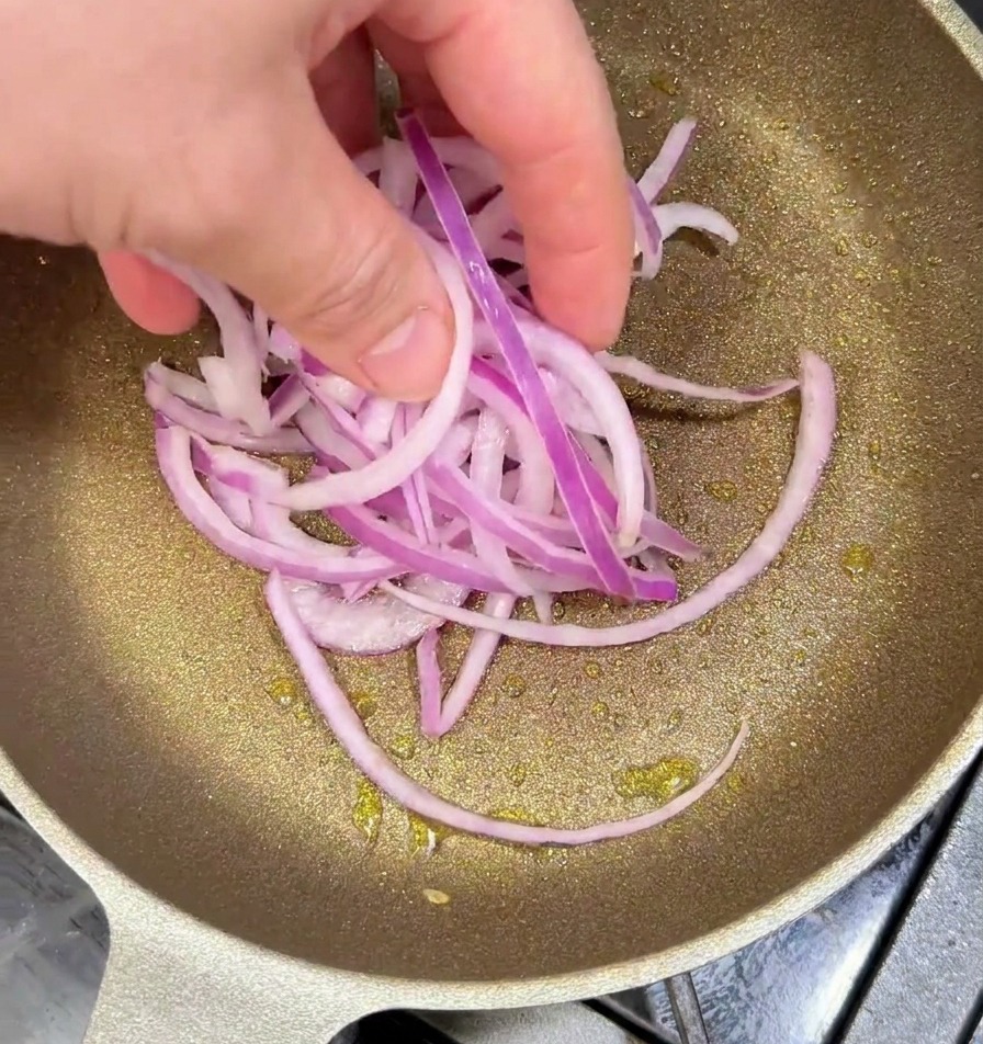 기름을 두른 팬에 채 썬 적양파를 넣고 노릇하게 볶는 모습.
