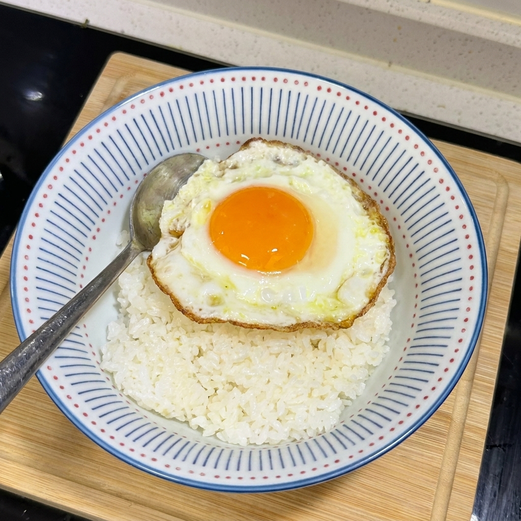 흰 쌀밥 위에 노른자가 살아있는 써니사이드업 달걀 프라이를 올린 모습.