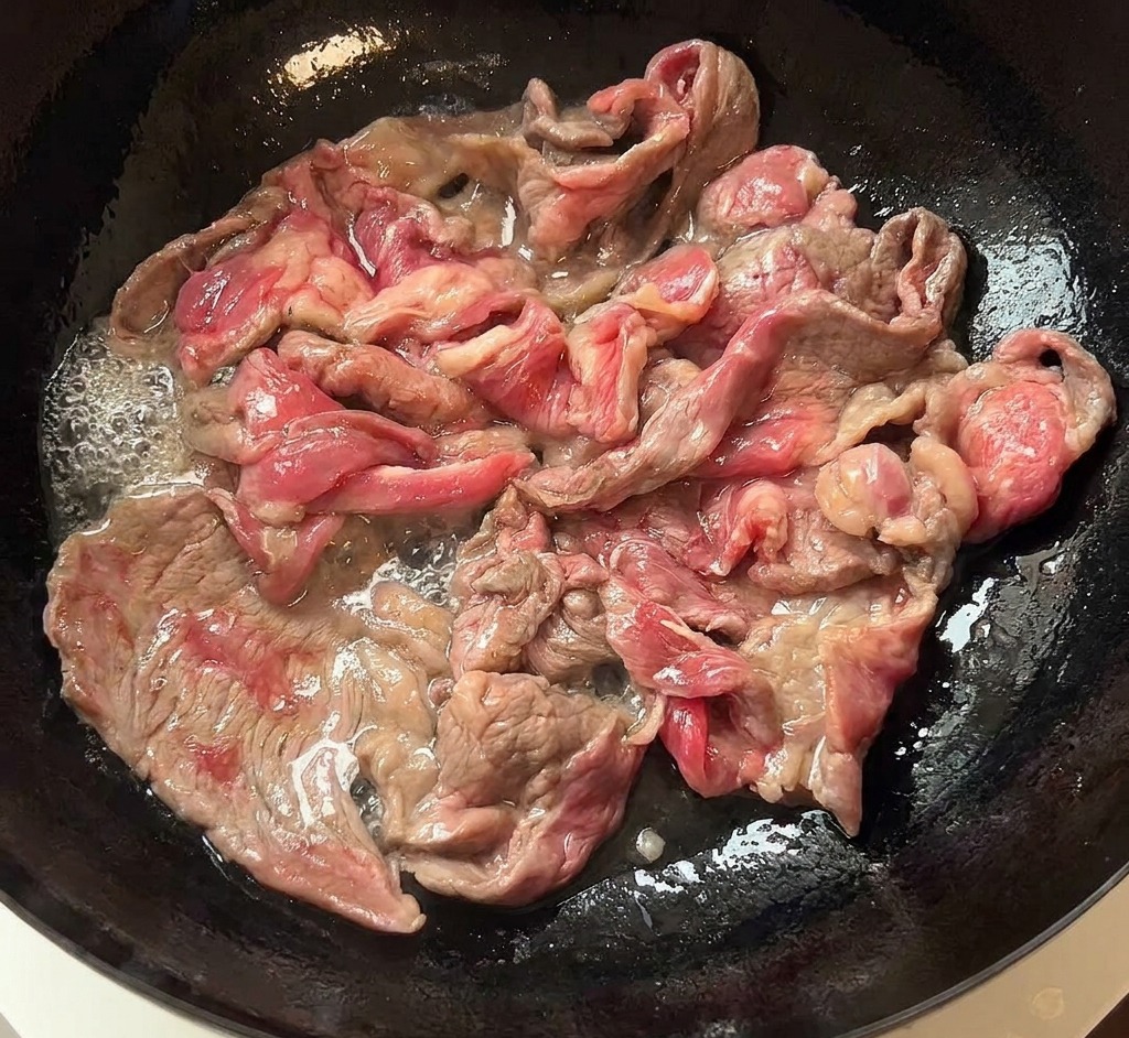 팬에서 노릇하게 구워진 소고기를 흰 접시로 옮기는 모습.