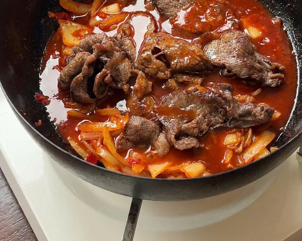 진한 빨간 양념이 보글보글 끓으며 소고기와 김치에 배어드는 모습.