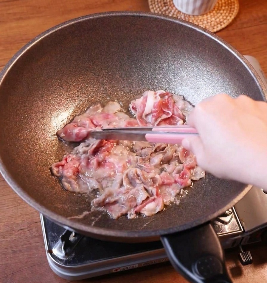 팬에서 노릇하게 익은 고기를 집게로 건져내는 모습