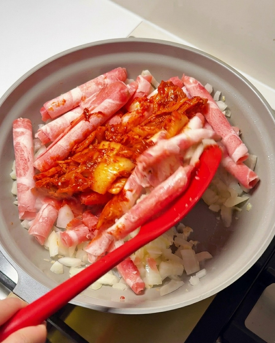 소고기와 채소가 담긴 팬에 붉은 김치 양념을 투하하는 모습.