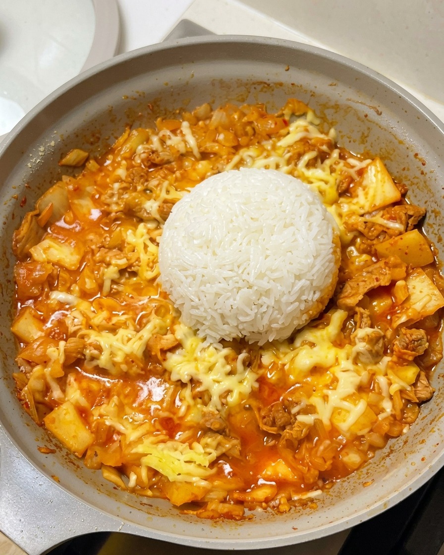 치즈와 고기가 깔린 팬 정중앙에 둥글게 모양을 잡은 밥을 올린 모습.