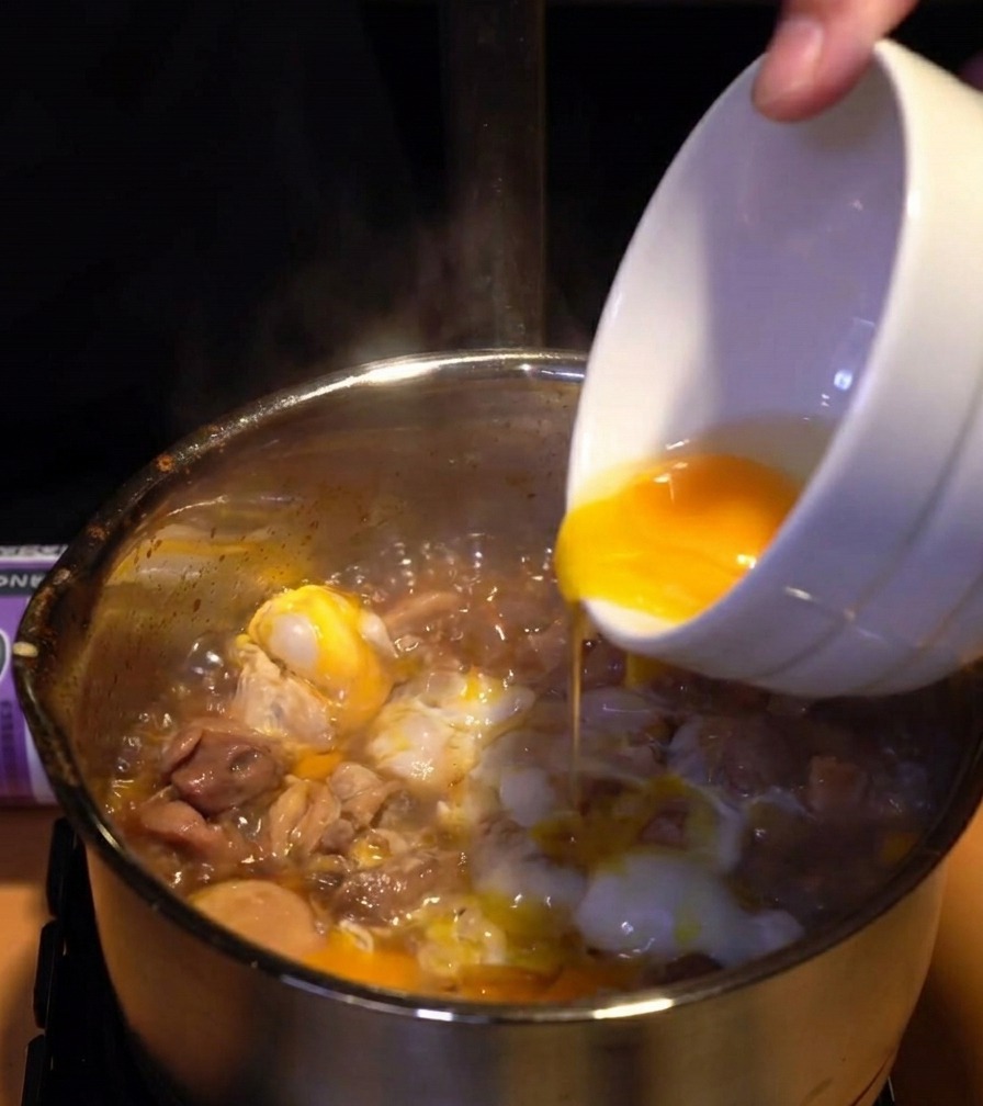 반쯤 익은 흰자 위로 선명한 노란색 노른자를 덧입히듯 붓는 모습.