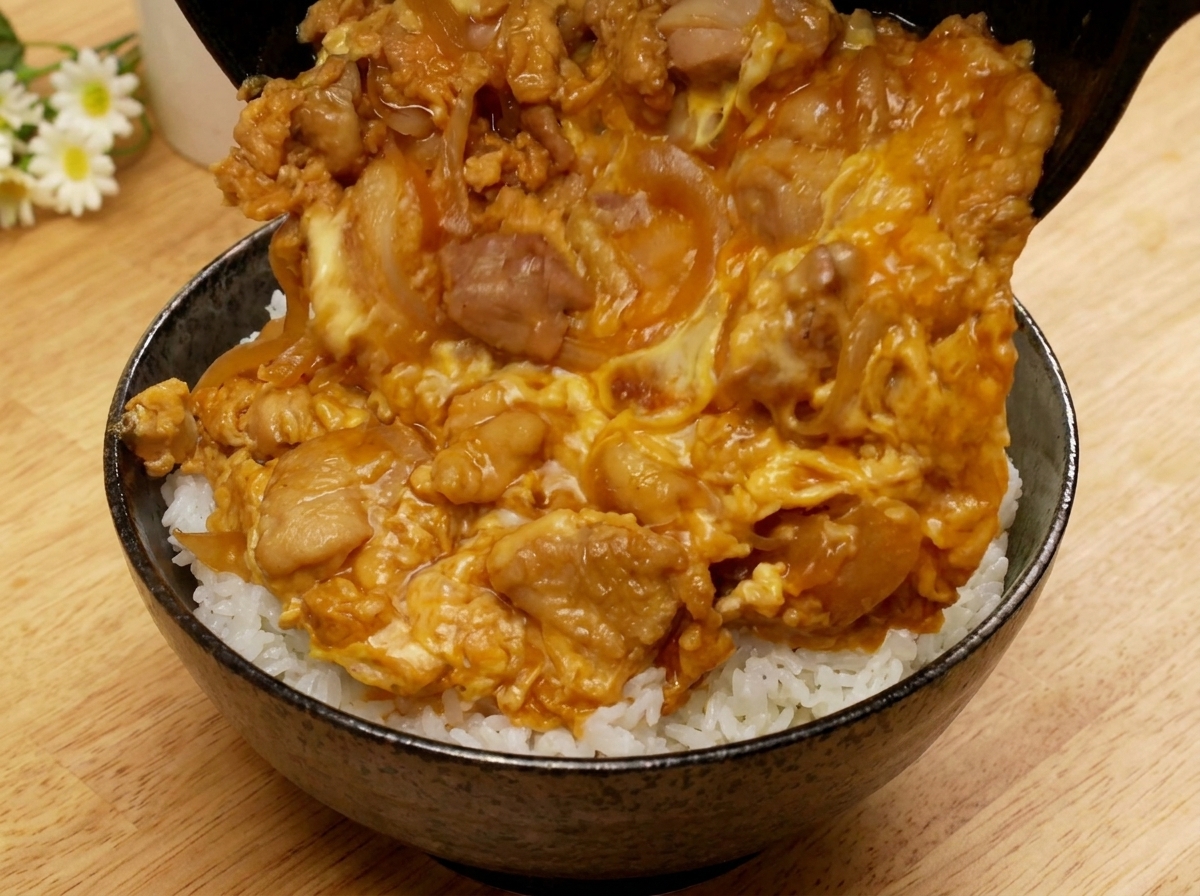 프라이팬을 기울여 완성된 요리를 따뜻한 흰쌀밥 위에 매끄럽게 미끄러뜨리는 모습.