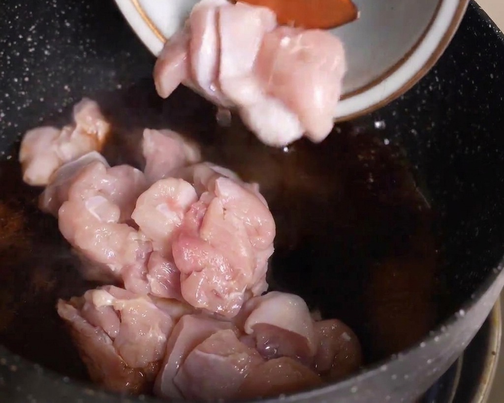 끓는 양념 소스에 슬라이스한 닭고기를 넣는 모습.