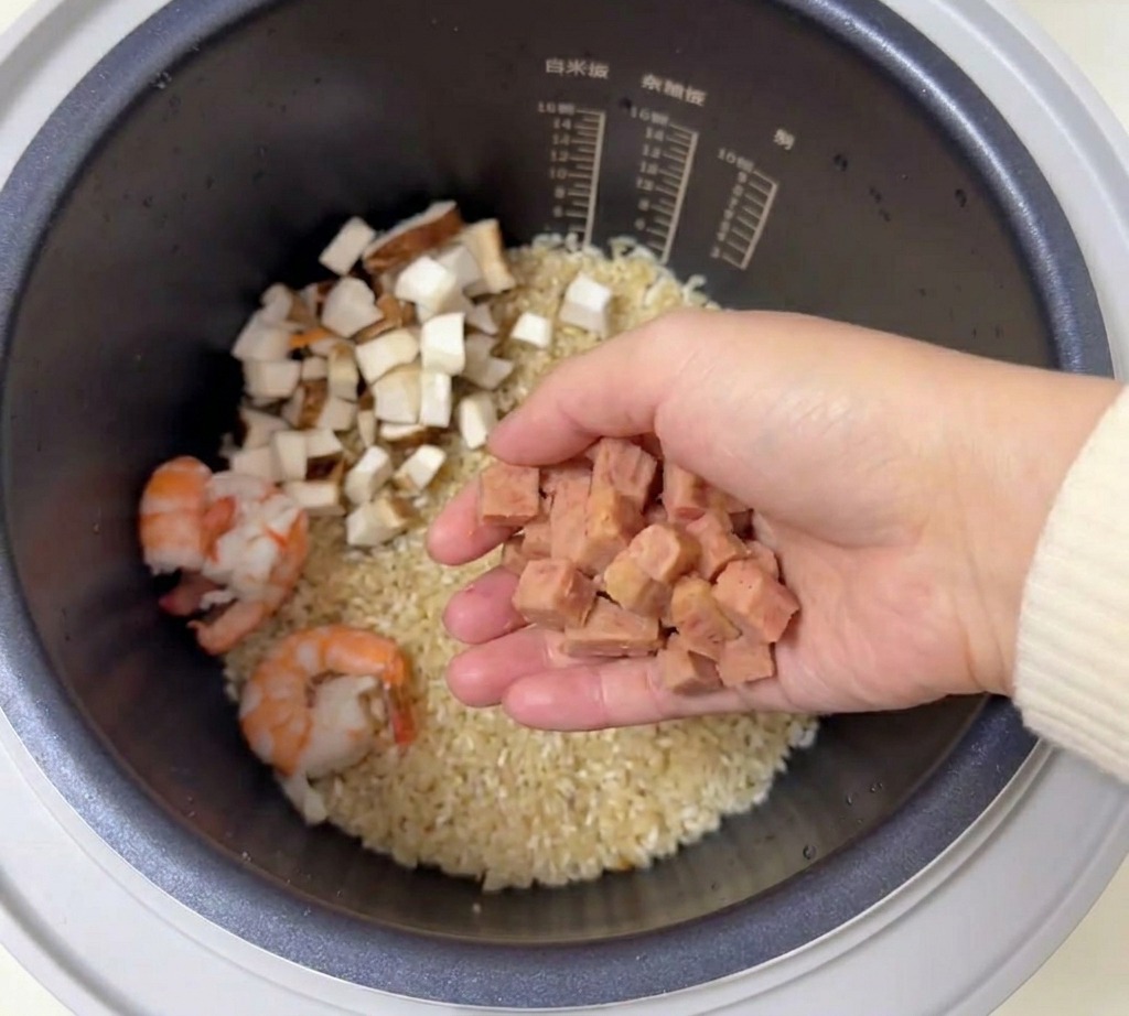 새우와 쌀이 담긴 밥솥 위로 깍둑썰기한 스팸을 올리는 모습.
