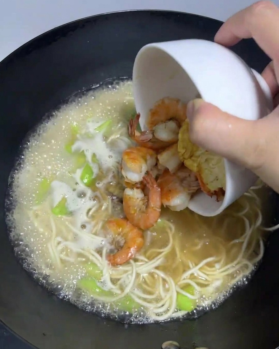 익힌 새우와 달걀 프라이를 끓는 라면 웍에 다시 넣는 모습