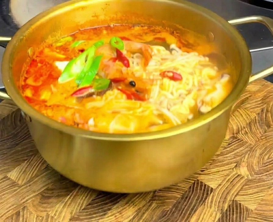 완성된 해물 라면 위에 어긋썰기한 고추를 올려 나무 도마 위에 차려낸 모습.