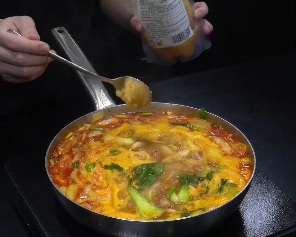 끓는 짬뽕 국물에 다진 마늘과 각종 양념을 추가하는 모습