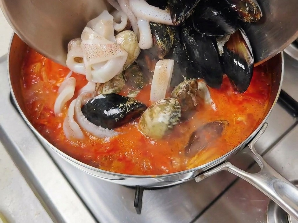 끓는 국물에 조개와 오징어를 넣는 모습