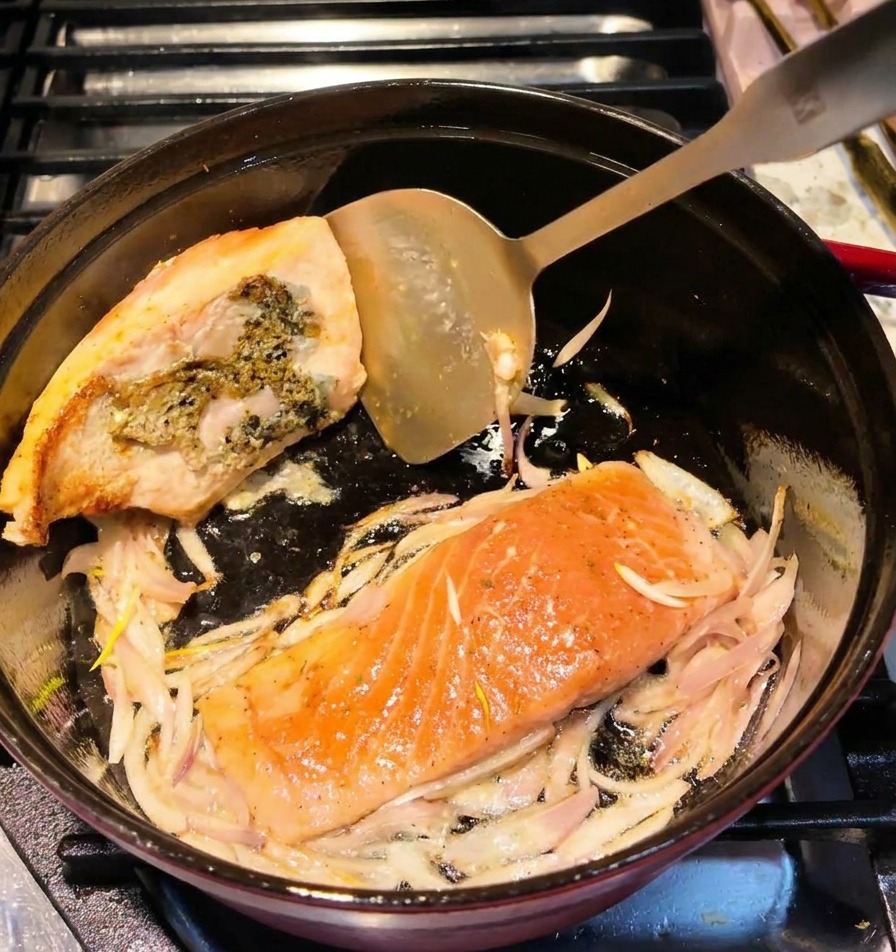 뒤집개로 연어를 뒤집어 노릇하게 구워진 단면을 보여주는 모습.