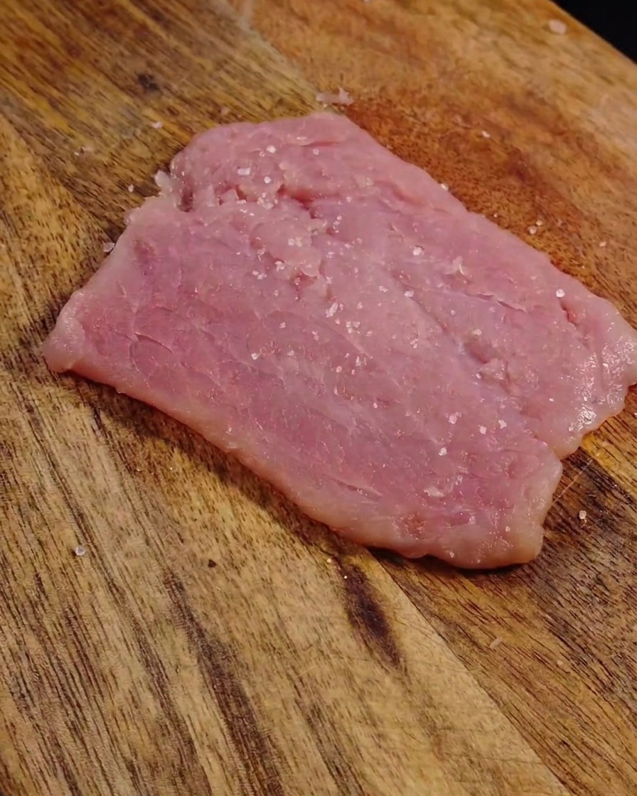 넓게 편 돼지고기 표면에 뿌려진 소금과 후추