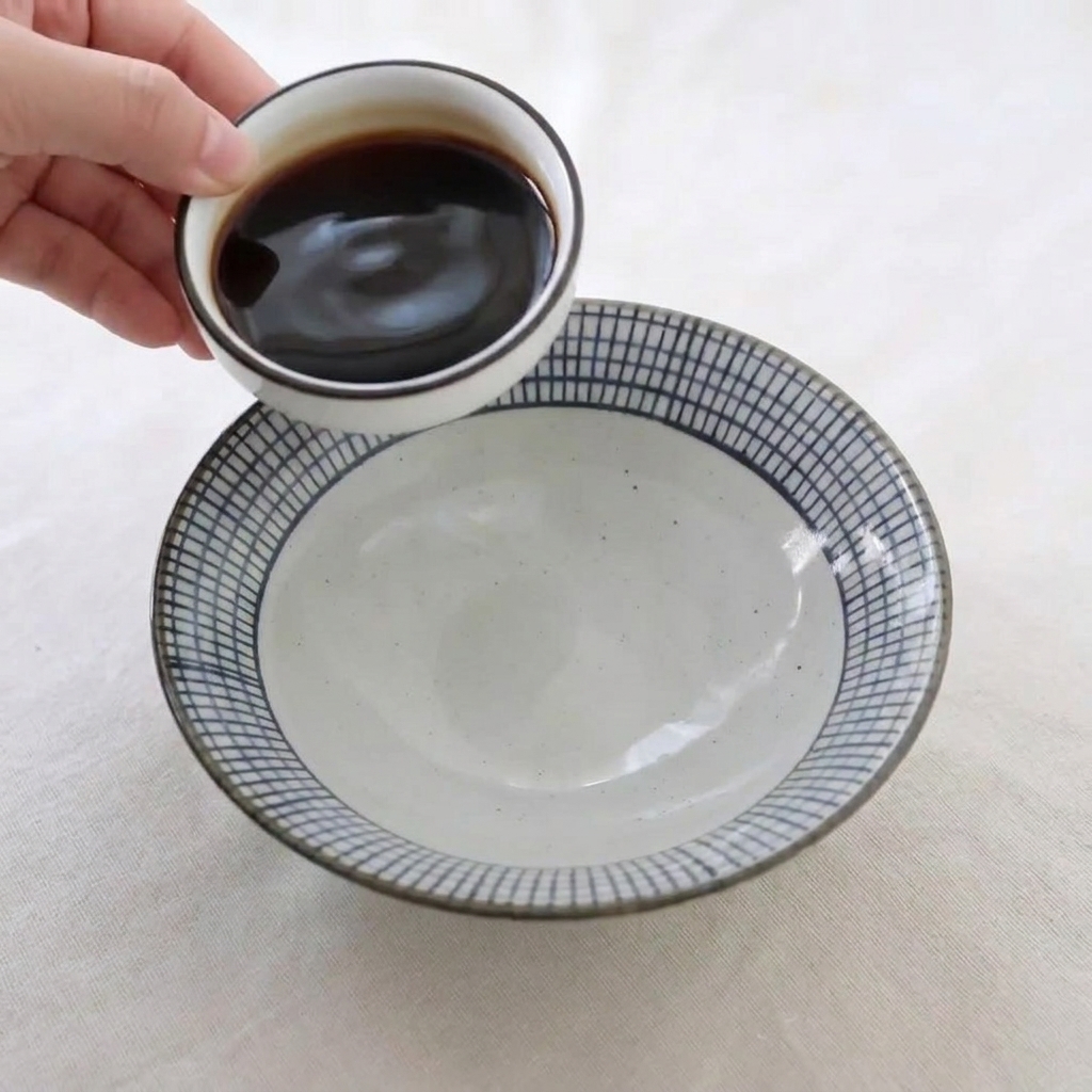 작은 그릇에 담긴 간장과 꿀 등의 재료를 세라믹 볼에 부어 소스를 만드는 장면.