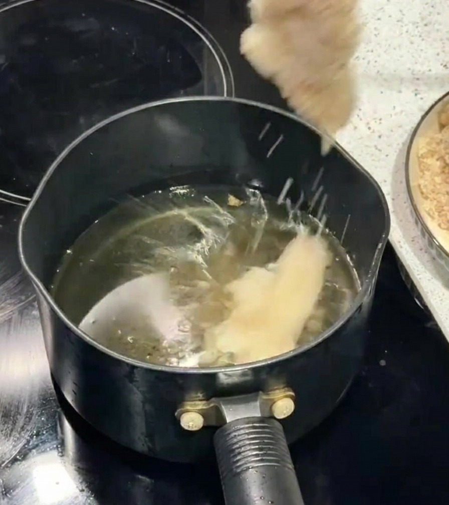 젓가락을 이용해 빵가루를 입힌 고기를 끓는 기름 솥에 넣는 장면