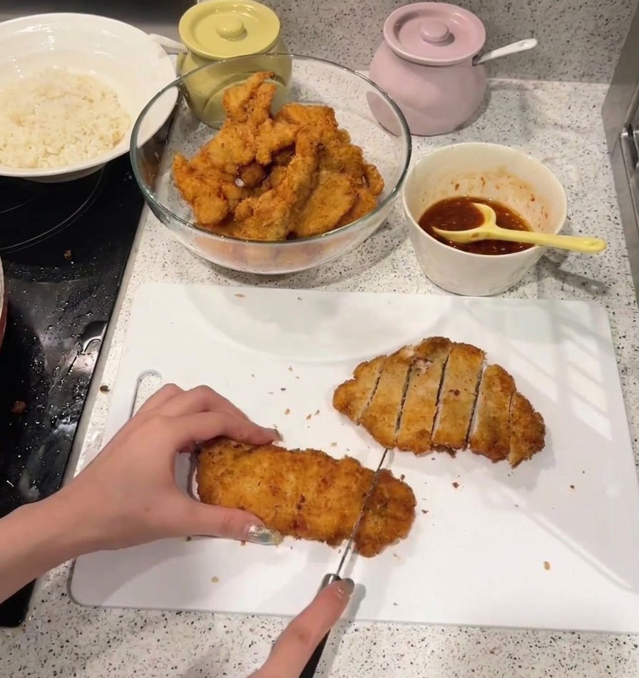 바삭하게 튀겨진 치킨카츠를 도마 위에서 일정한 간격으로 써는 모습