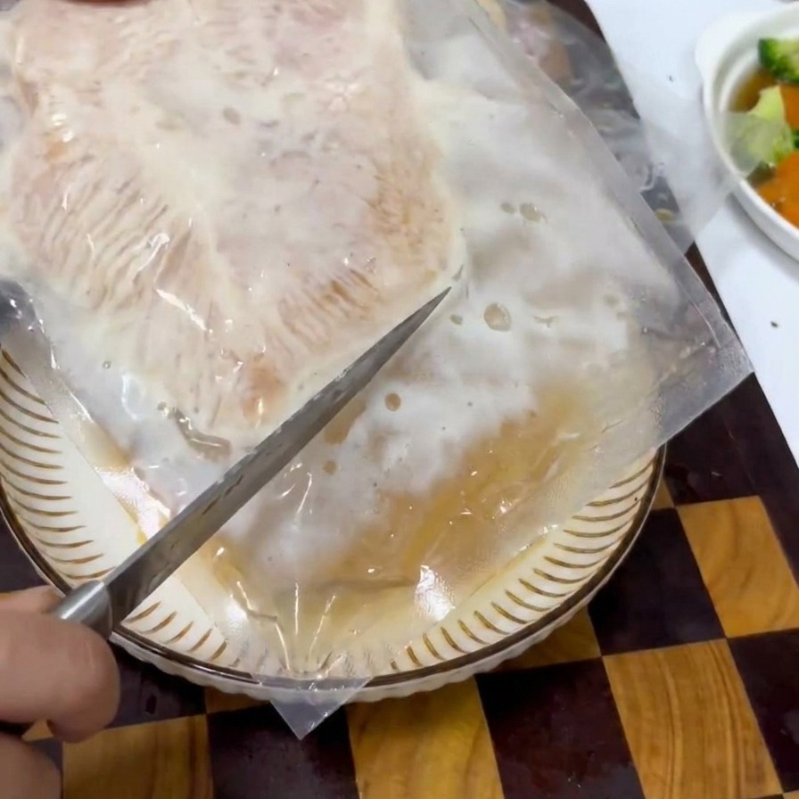 진공 포장된 양념 닭고기 팩을 뜯는 모습