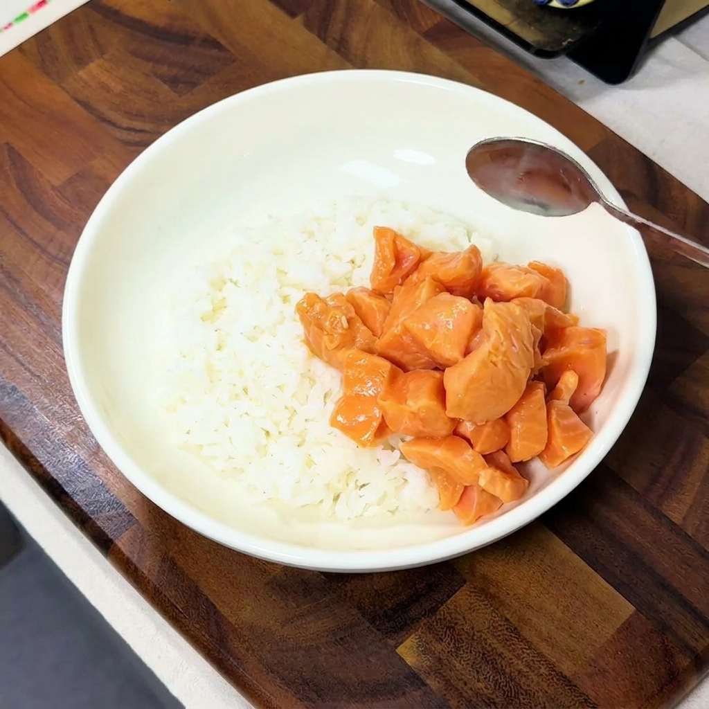 갓 지은 밥 위에 양념된 연어를 정성스럽게 올리는 모습