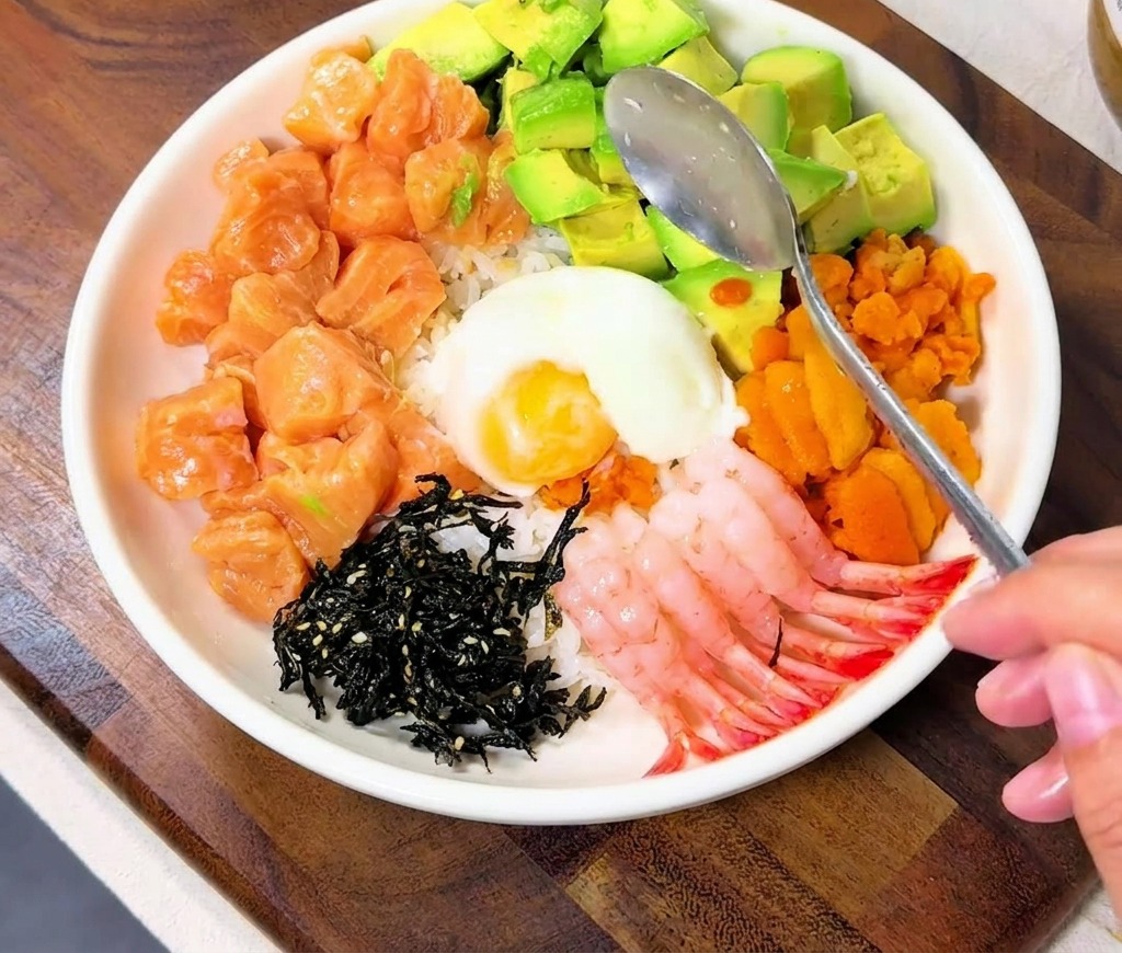 화려한 해산물 토핑 중앙에 온천 계란을 올리는 모습