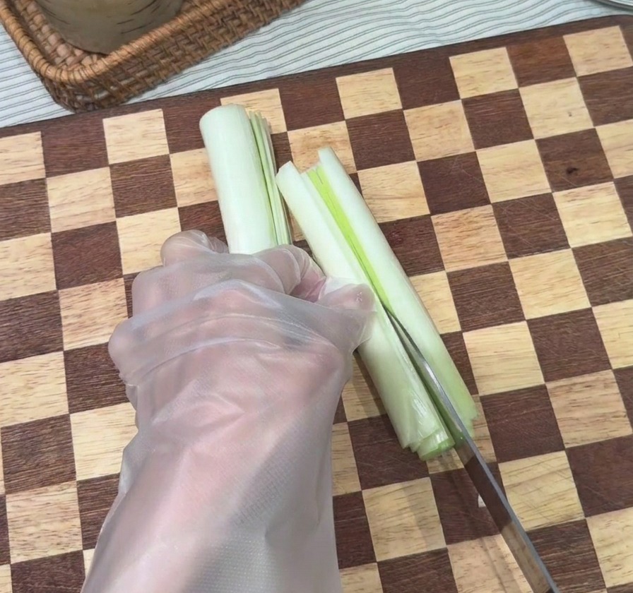 도마 위에서 신선한 대파를 가늘고 길게 채 써는 모습