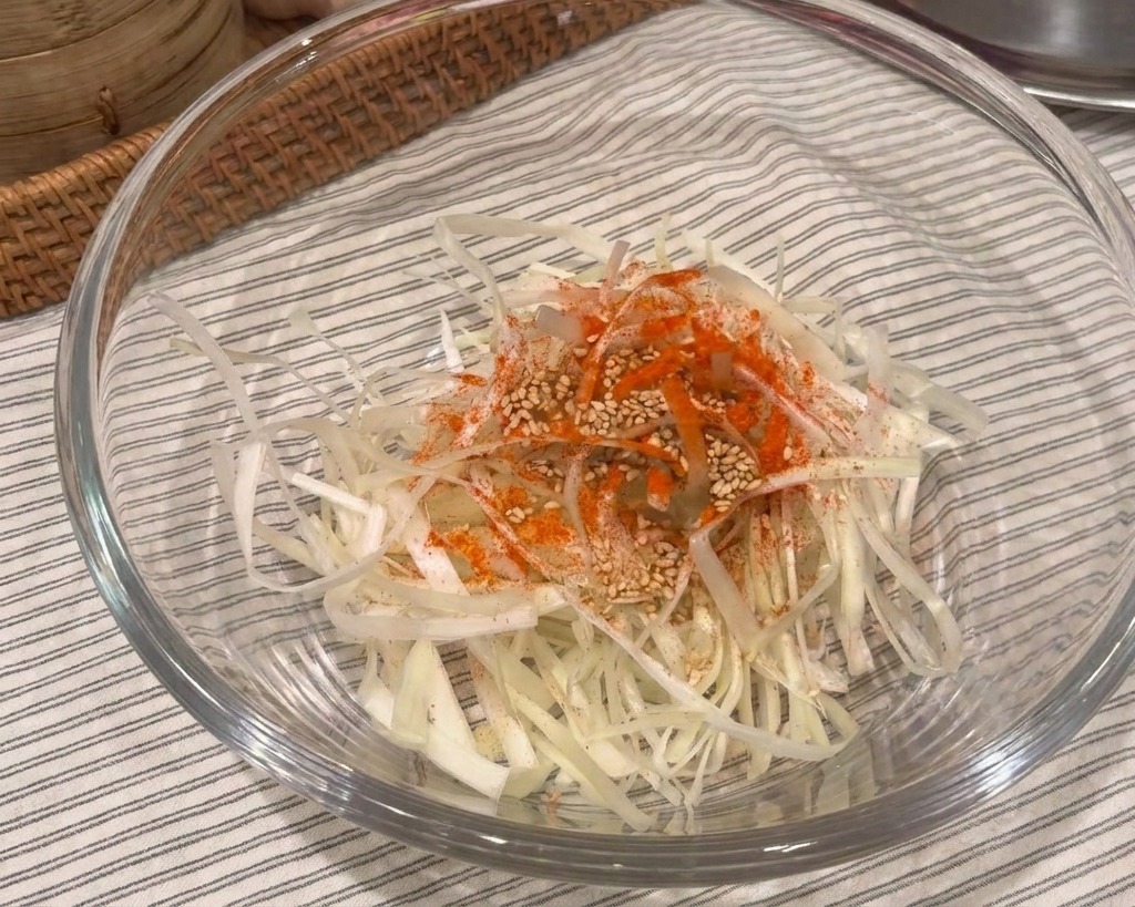 유리볼에 담긴 파채 위에 고춧가루와 참깨가 넉넉히 뿌려진 모습
