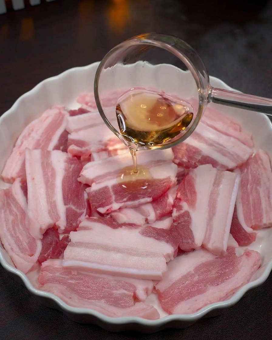 삼겹살 위에 투명한 맛술을 붓는 모습