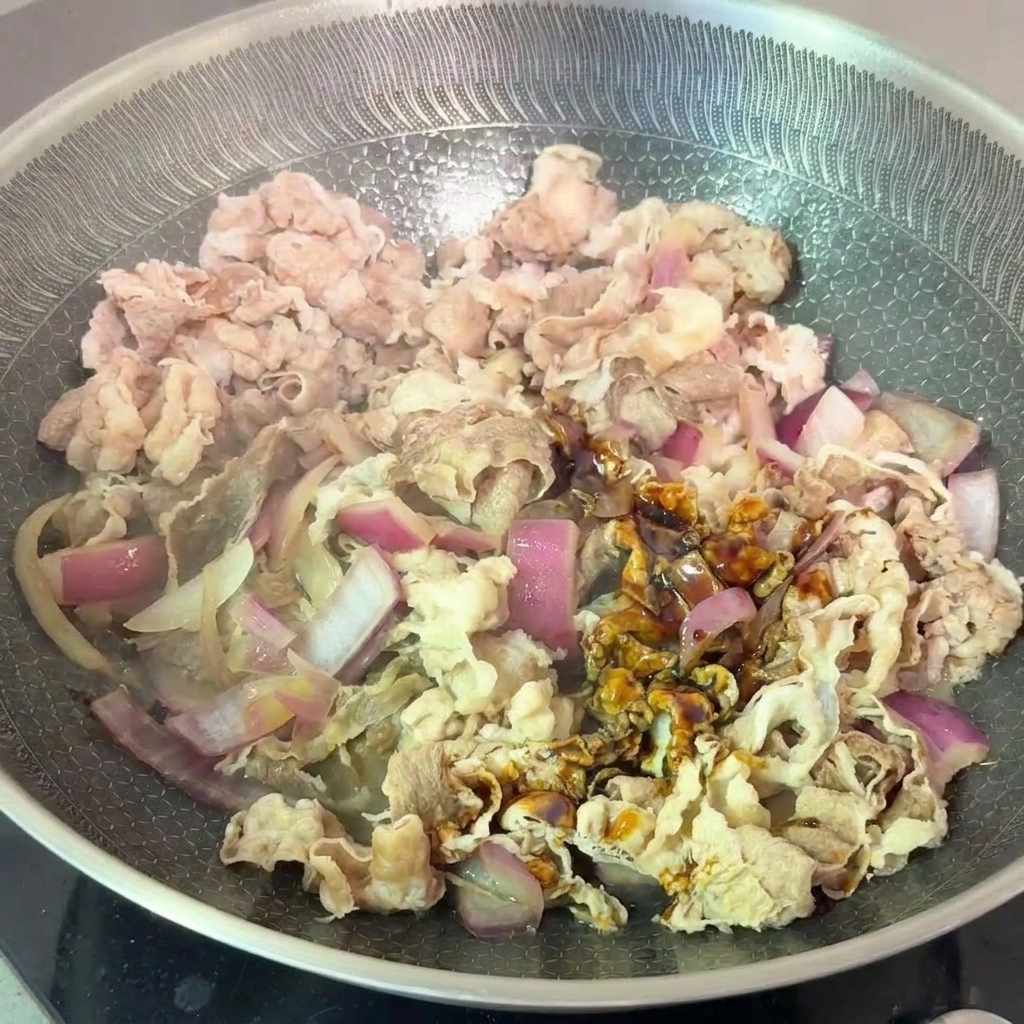 볶은 양파와 소고기에 양념장을 부어 함께 졸이는 모습.