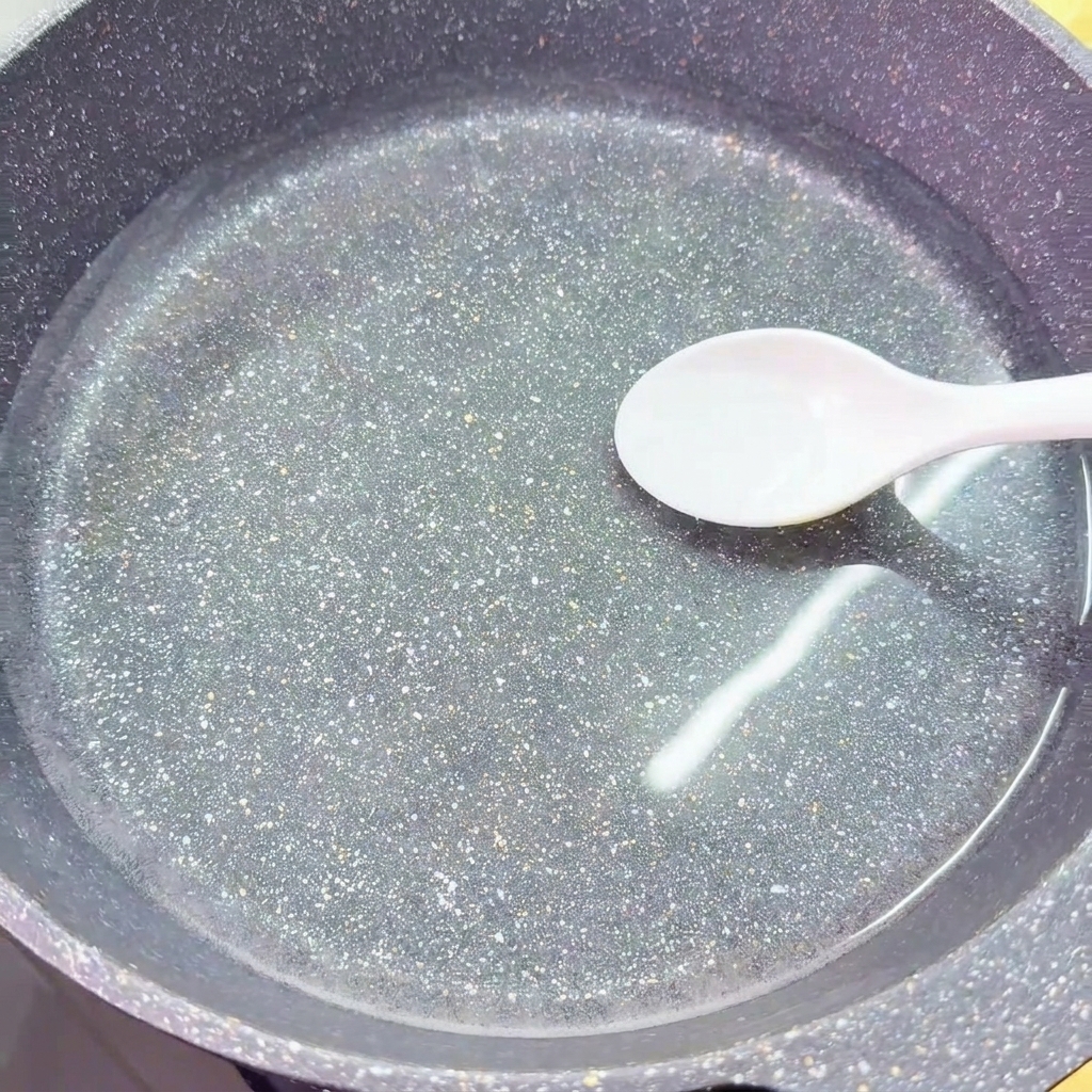 차가운 물이 담긴 워크에 흰 숟가락으로 소금을 넣는 모습.