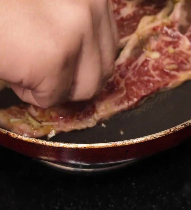 달궈진 프라이팬에 갈비 한 대를 올리고 있는 모습.