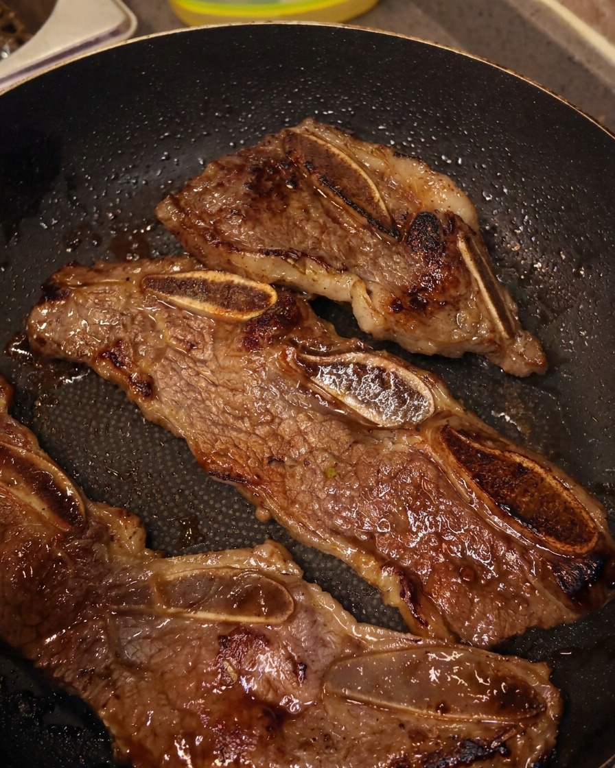 팬 위에서 주방 가위로 갈비 뼈 사이를 자르는 모습.