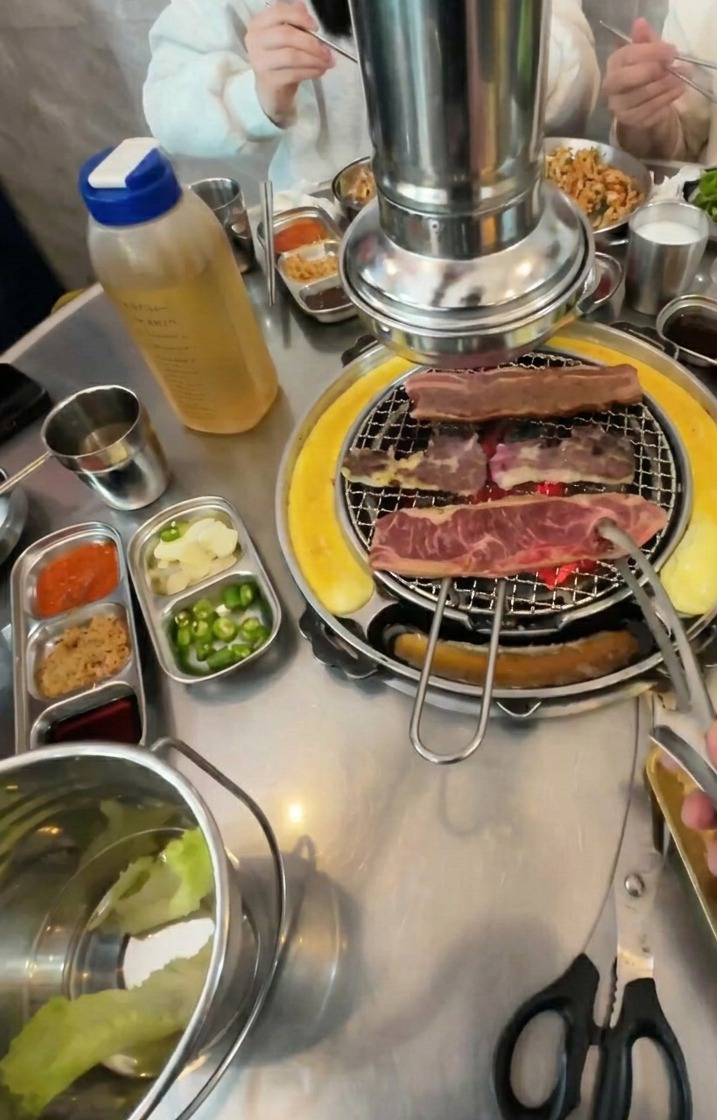 숯불 위에서 갈색으로 먹음직스럽게 익어가는 소갈비를 뒤집는 모습.
