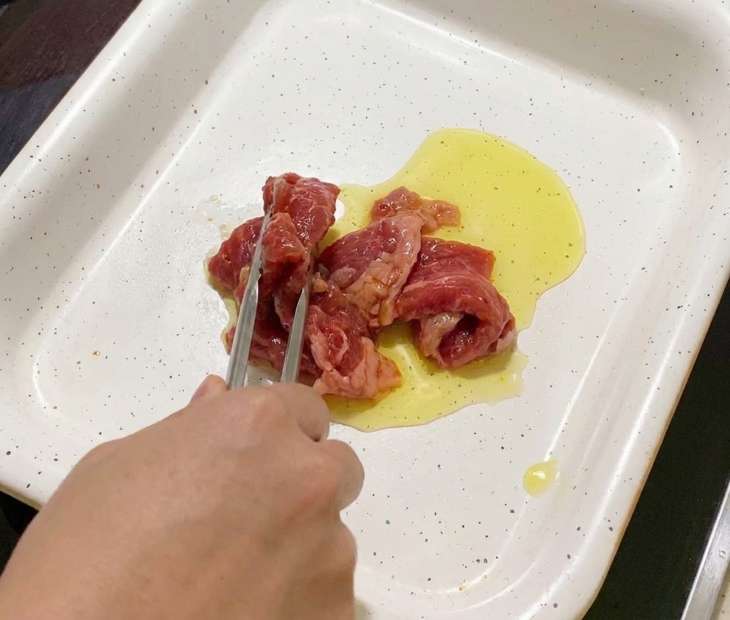 달궈진 팬에 기름을 두르고 밑간한 돼지고기를 올리는 모습