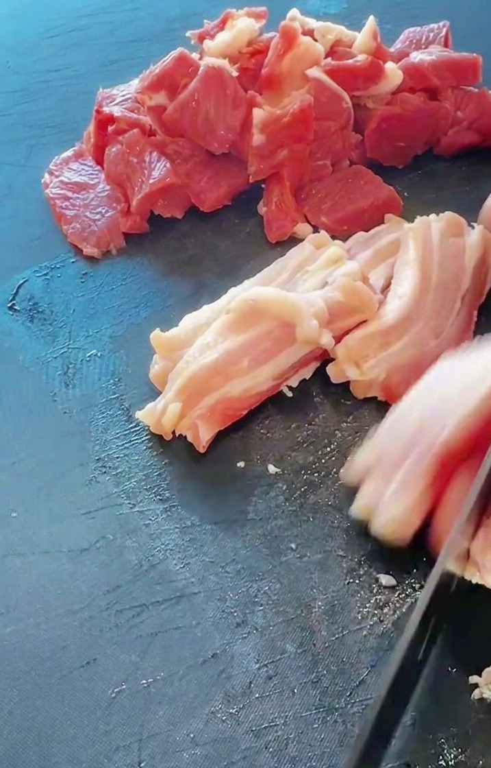 도마 위에서 돼지 삼겹살과 뒷다리살을 먹기 좋은 크기로 썰고 있는 모습.