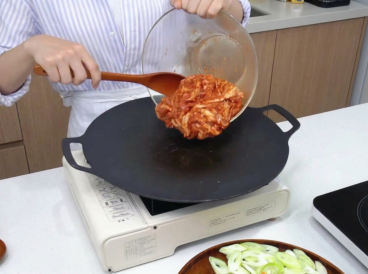 달궈진 팬 위에 양념된 제육볶음을 올리고 펴는 모습